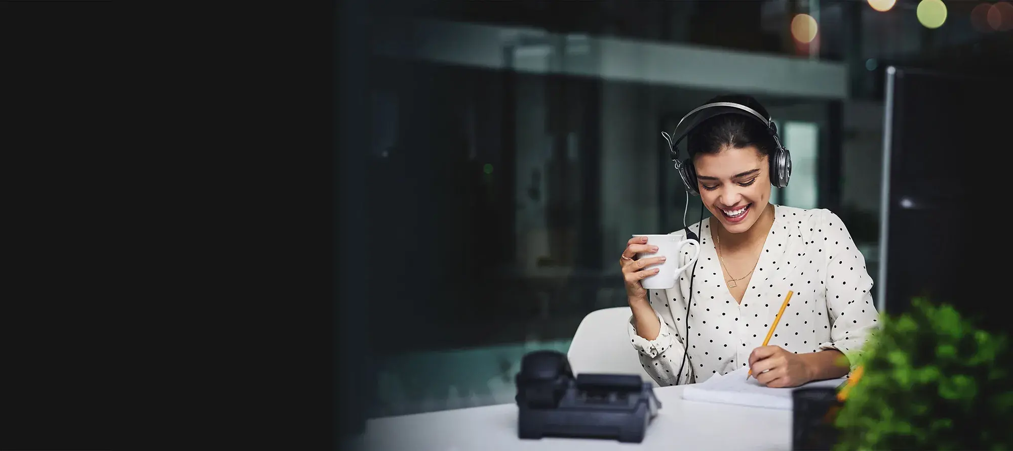 A smiling woman with a headset on taking notes