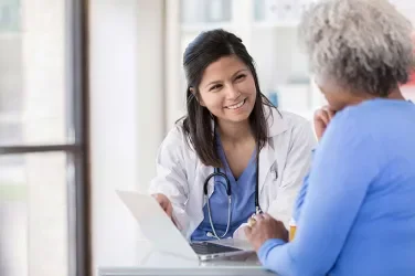 Medical professional and patient smiling while reviewing laptop