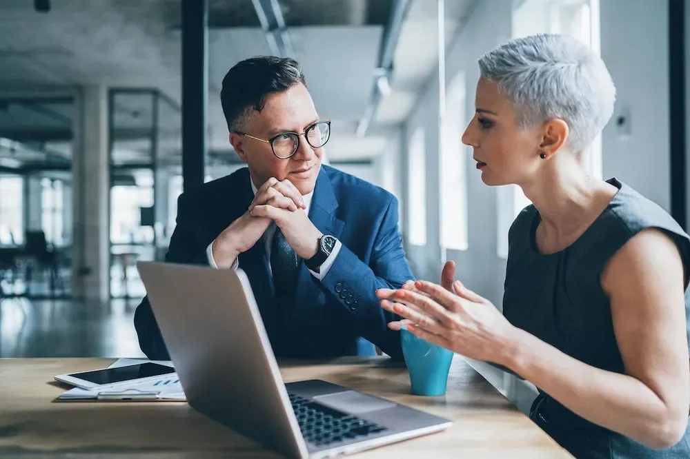 Man and woman having conversation in front of computer