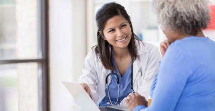 Medical professional and patient smiling while reviewing laptop