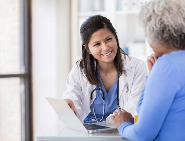 Medical professional and patient smiling while reviewing laptop